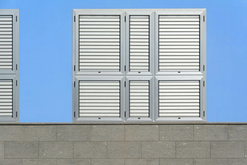 Nowoczesne aluminiowe okna z żaluzjami w jasnej elewacji budynku – estetyka i funkcjonalność.