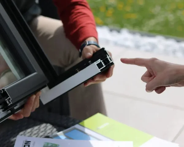 Doradztwo techniczne dotyczące profilu aluminiowego okna — klient wskazuje element ramy.