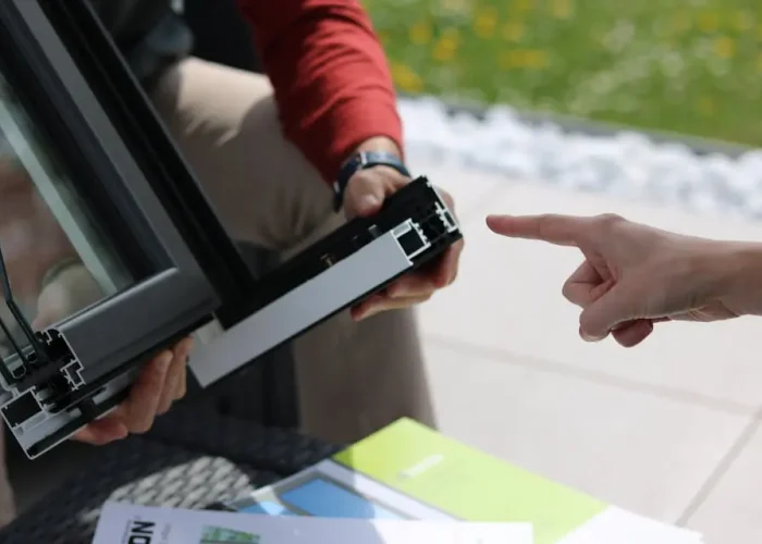 Doradztwo techniczne dotyczące profilu aluminiowego okna — klient wskazuje element ramy.